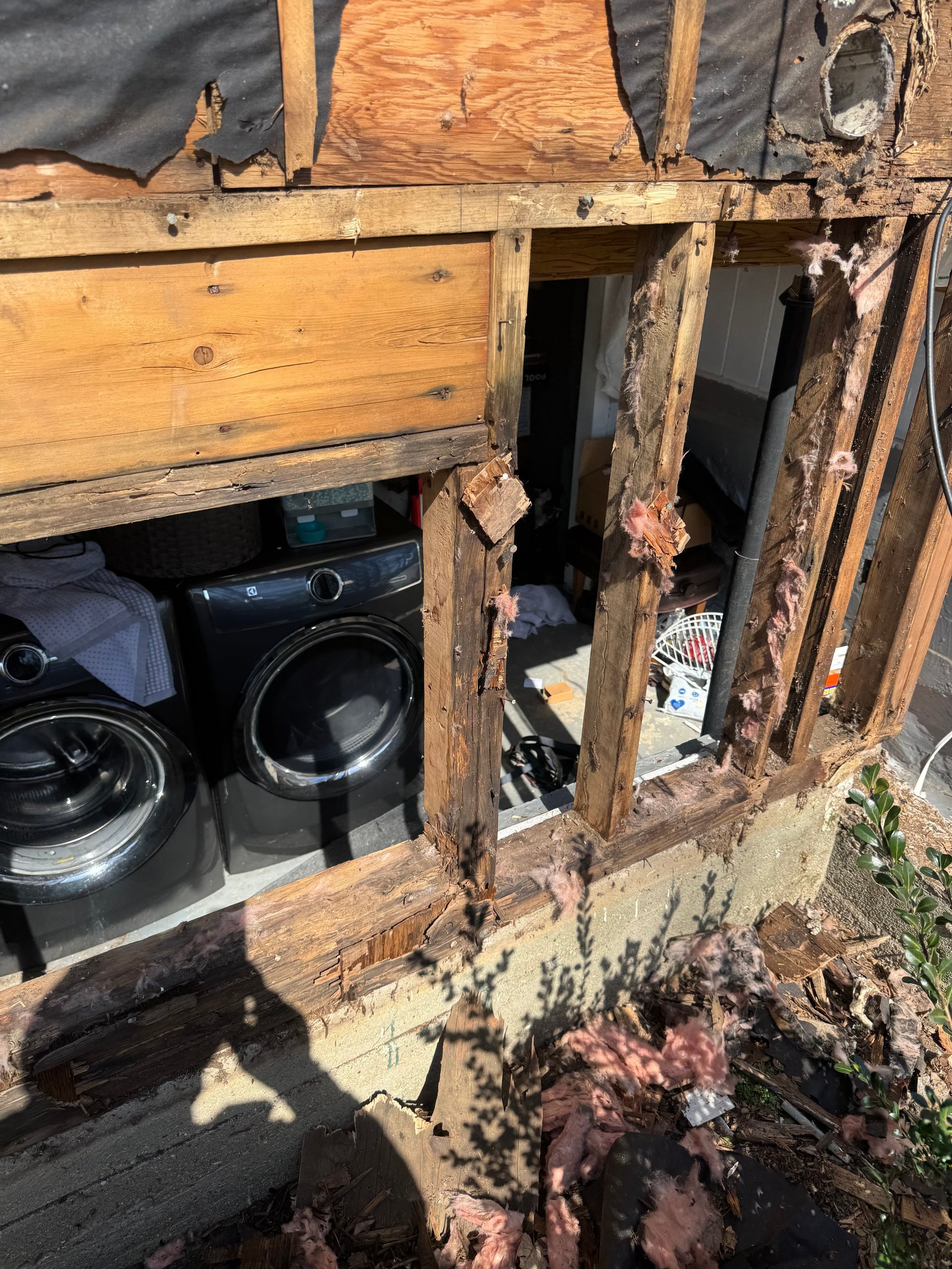 Weathered wooden storage unit with open doors revealing washing machine and other items inside